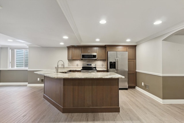 kitchen with stainless steel appliances, light wood-type flooring, light stone countertops, ornamental molding, and sink