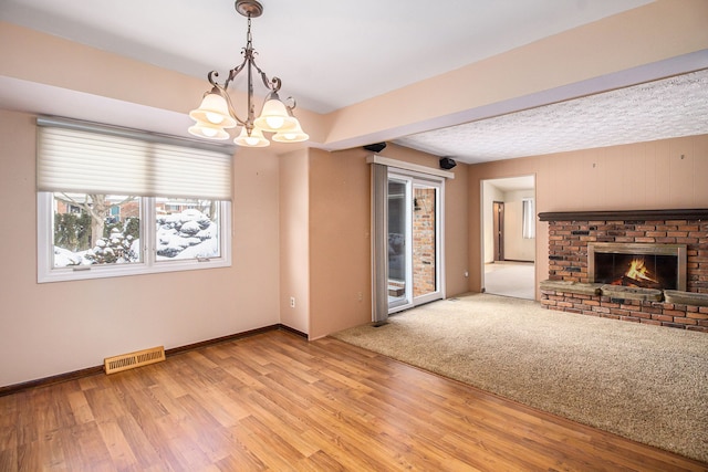 unfurnished living room featuring light hardwood / wood-style floors, a notable chandelier, and a fireplace