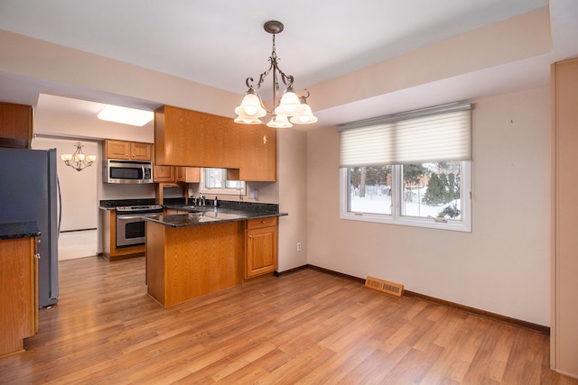 kitchen with light hardwood / wood-style flooring, a notable chandelier, stainless steel appliances, pendant lighting, and kitchen peninsula