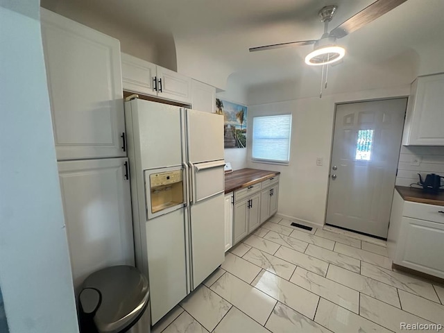 kitchen with wooden counters, ceiling fan, backsplash, white fridge with ice dispenser, and white cabinets