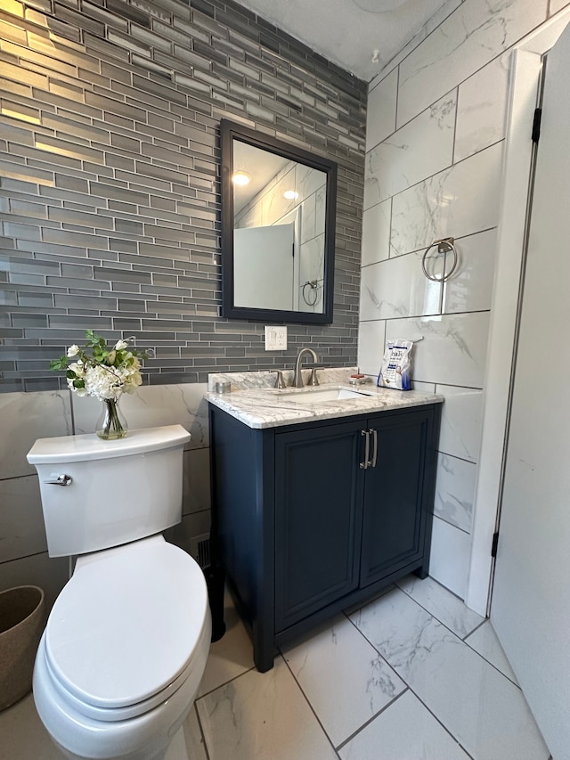 bathroom featuring vanity, tile walls, and toilet