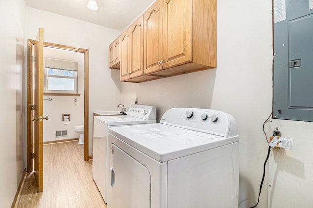 washroom featuring washing machine and dryer, cabinets, and electric panel