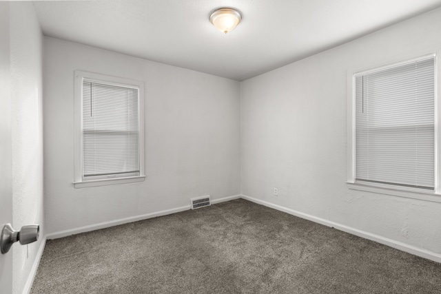 spare room with dark carpet