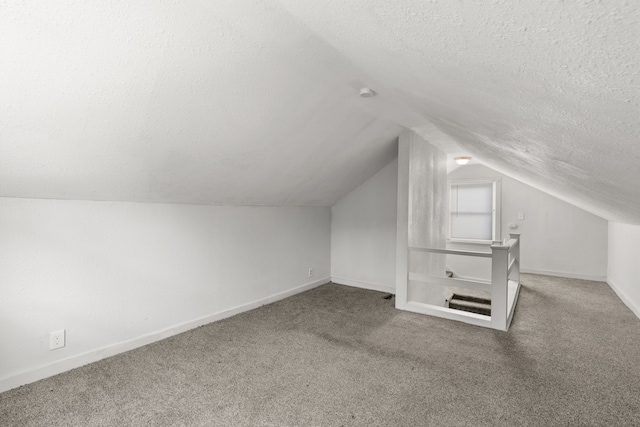 additional living space featuring carpet floors, a textured ceiling, and vaulted ceiling