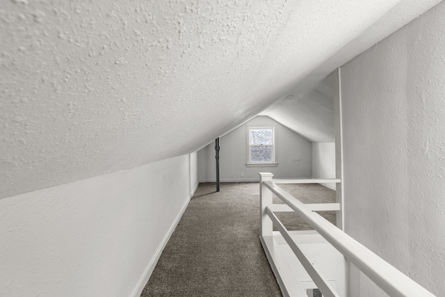 additional living space featuring vaulted ceiling, a textured ceiling, and dark colored carpet