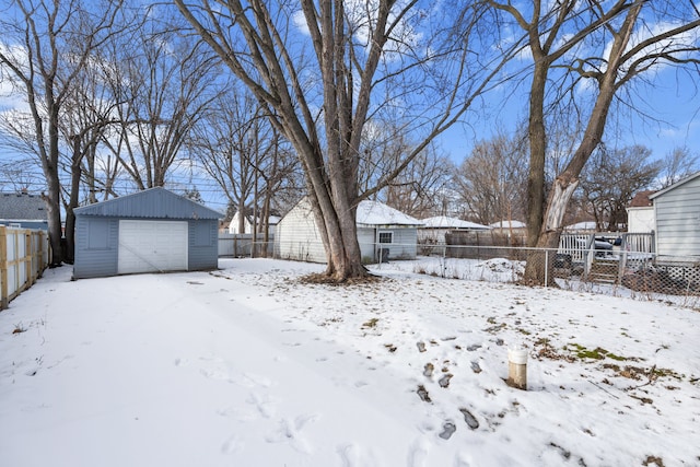 snowy yard featuring a garage and an outbuilding