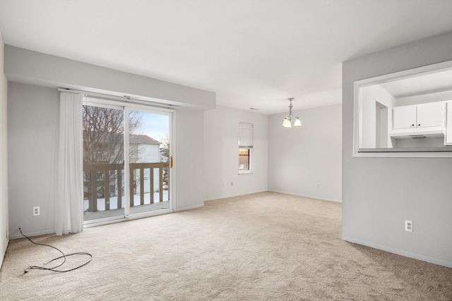 spare room featuring light colored carpet and an inviting chandelier