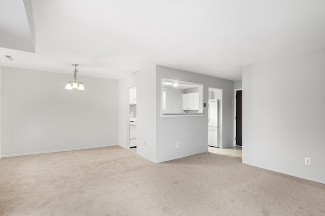 unfurnished living room featuring light colored carpet and an inviting chandelier