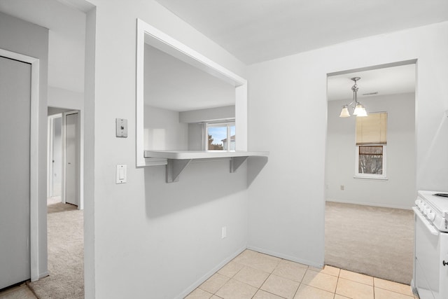 kitchen featuring decorative light fixtures, light colored carpet, and white stove