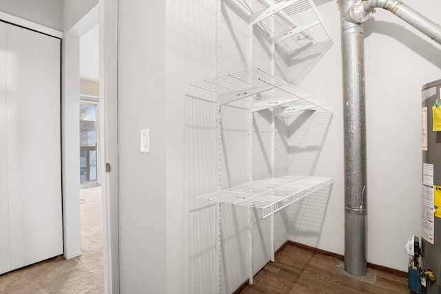 spacious closet featuring hardwood / wood-style flooring and water heater