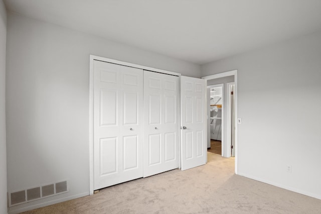 unfurnished bedroom with a closet and light carpet