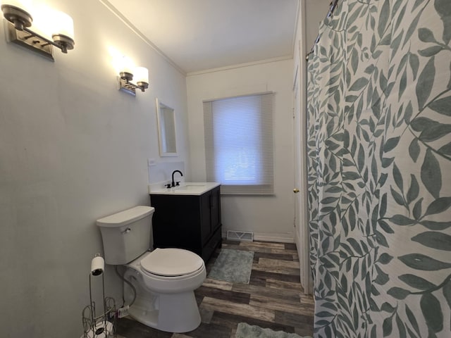 bathroom with toilet, crown molding, wood-type flooring, and vanity