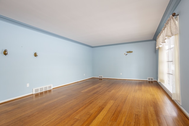 spare room featuring wood-type flooring and crown molding