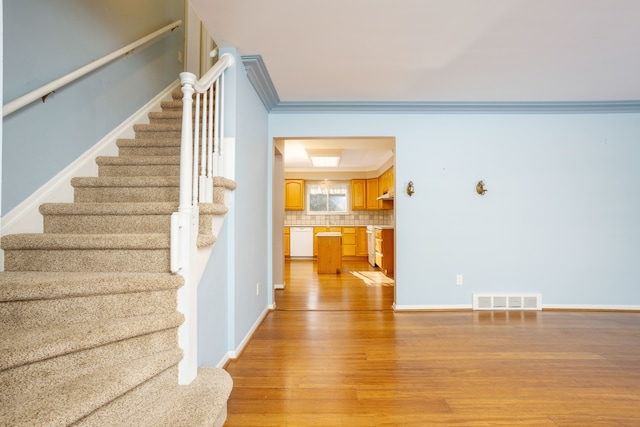 stairs featuring crown molding and hardwood / wood-style flooring