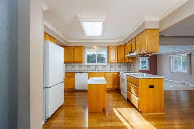 kitchen featuring white appliances, crown molding, tasteful backsplash, and a center island