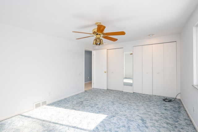 unfurnished bedroom with ceiling fan, carpet floors, and multiple closets