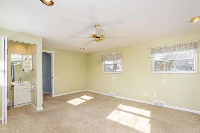 unfurnished bedroom featuring connected bathroom, ceiling fan, light colored carpet, and sink