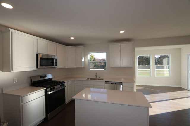 kitchen with white cabinets, appliances with stainless steel finishes, sink, and a kitchen island