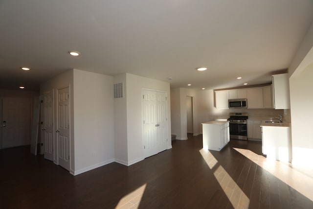 kitchen with sink, white cabinets, dark hardwood / wood-style floors, and stainless steel appliances