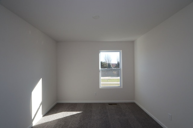 spare room featuring dark carpet