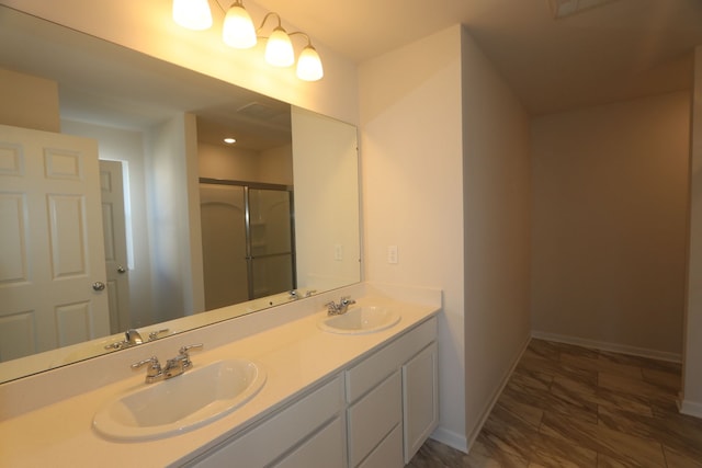 bathroom featuring a shower with shower door and vanity