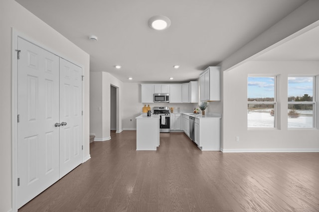 kitchen featuring dark hardwood / wood-style flooring, a kitchen island, white cabinets, and appliances with stainless steel finishes