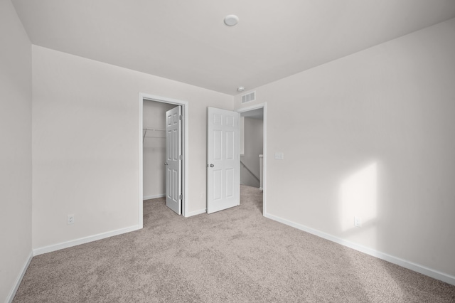 unfurnished bedroom with light colored carpet, a closet, and a walk in closet