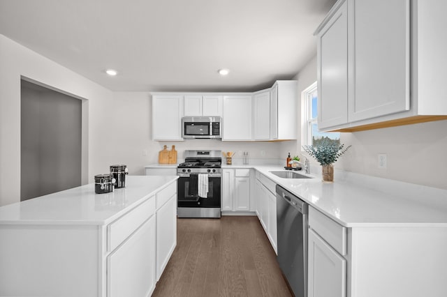 kitchen featuring sink, stainless steel appliances, white cabinets, a kitchen island, and dark hardwood / wood-style flooring