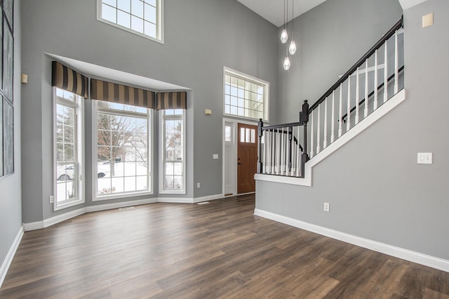 entryway featuring stairs, a high ceiling, baseboards, and wood finished floors