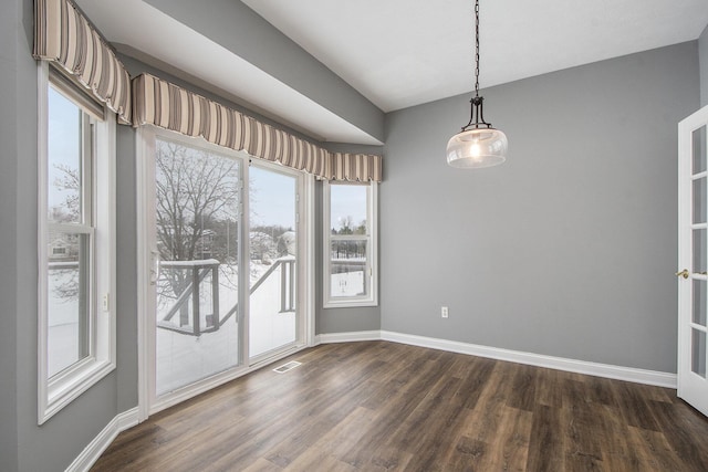 unfurnished dining area featuring dark wood-style flooring, visible vents, and baseboards