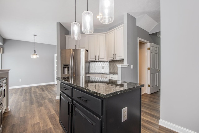 kitchen with dark wood finished floors, dark stone counters, decorative backsplash, stainless steel fridge with ice dispenser, and dark cabinets