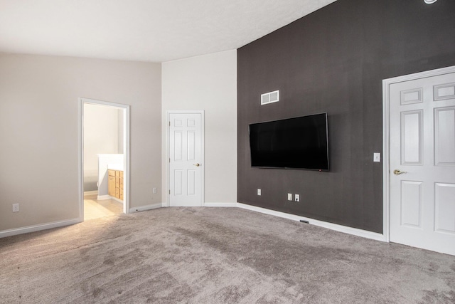 unfurnished living room featuring lofted ceiling, carpet, visible vents, and baseboards