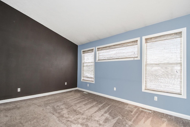 carpeted empty room with baseboards and vaulted ceiling