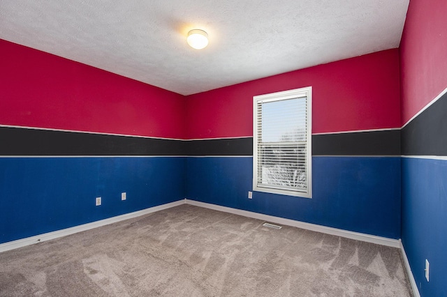 empty room featuring baseboards, carpet, visible vents, and a textured ceiling