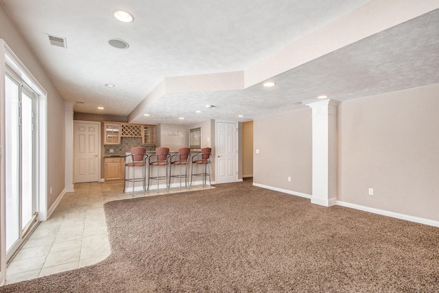 unfurnished living room featuring recessed lighting, light carpet, visible vents, a dry bar, and decorative columns