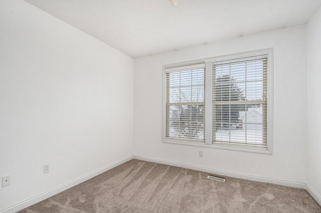 empty room with carpet, visible vents, and baseboards