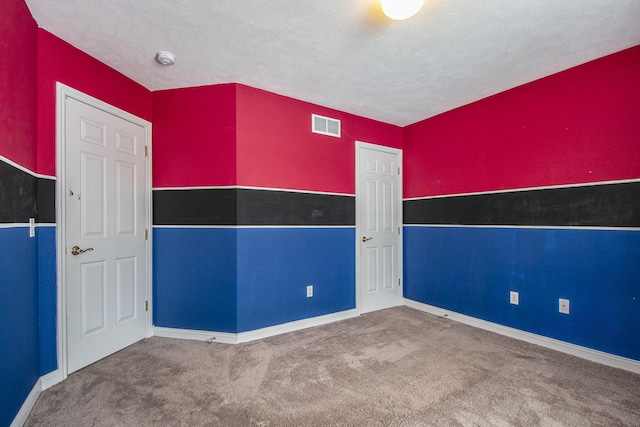 carpeted empty room with baseboards, visible vents, and a textured ceiling