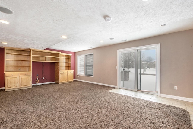 unfurnished living room with a textured ceiling, carpet floors, and baseboards