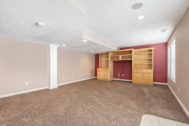 unfurnished living room featuring baseboards, visible vents, a textured ceiling, ornate columns, and dark carpet