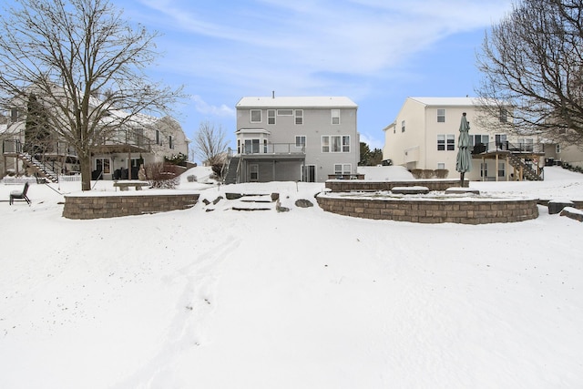 snow covered rear of property with stairway