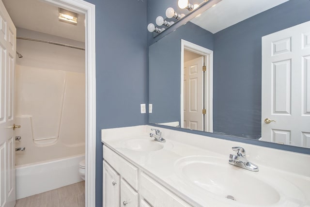 bathroom featuring toilet, shower / bath combination, double vanity, and a sink