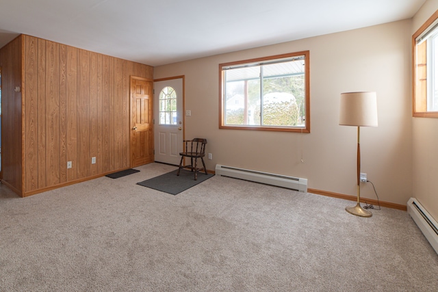 carpeted entrance foyer with wooden walls and a baseboard radiator