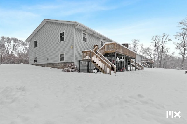 snow covered house with a wooden deck