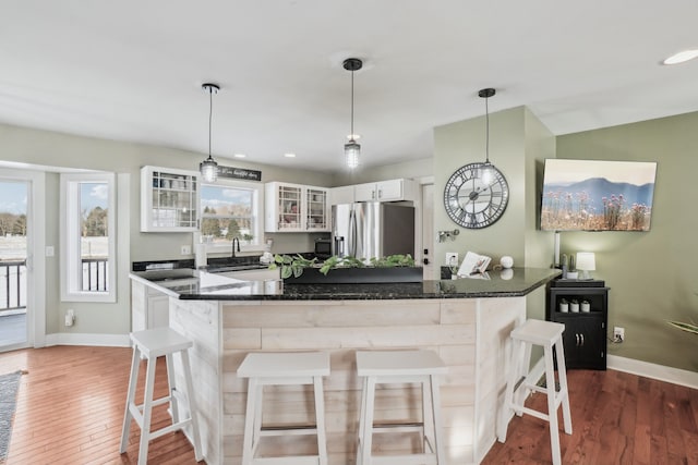 kitchen with a kitchen breakfast bar, pendant lighting, white cabinets, and stainless steel fridge