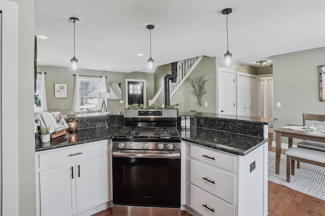 kitchen with white cabinetry, kitchen peninsula, stainless steel gas stove, dark stone counters, and pendant lighting