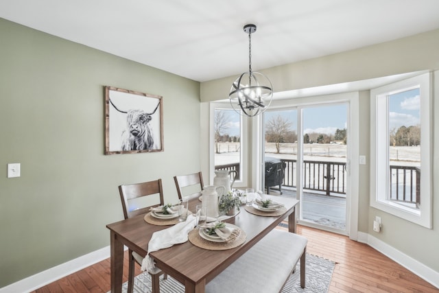 dining space with light hardwood / wood-style floors and a notable chandelier