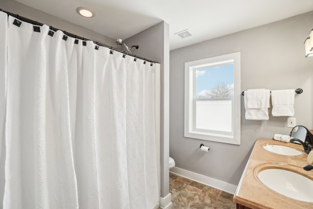 bathroom featuring toilet, vanity, and a shower with curtain