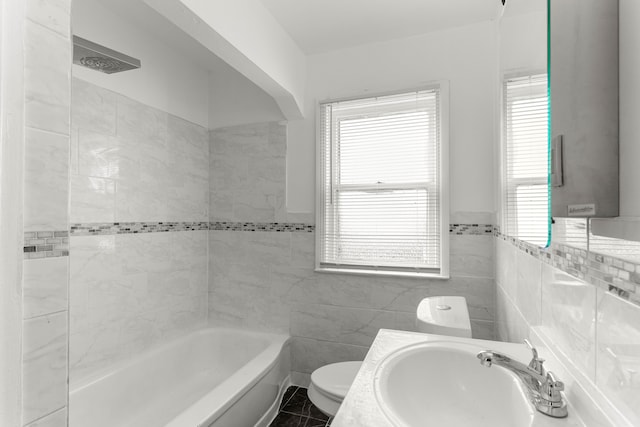 full bathroom featuring toilet, tile walls, tile patterned floors, shower / bathtub combination, and sink