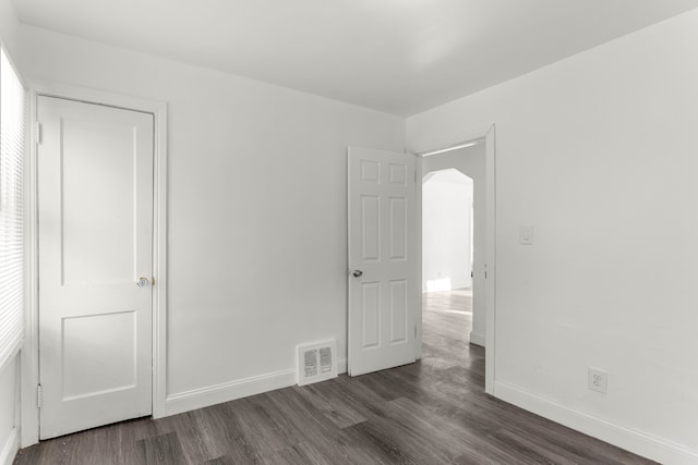 unfurnished bedroom featuring a closet and dark wood-type flooring