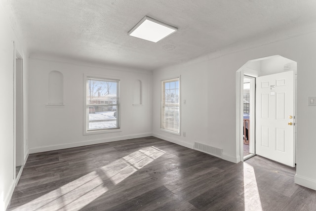 unfurnished room with a textured ceiling and dark hardwood / wood-style floors